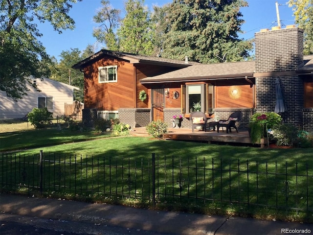 view of front of home featuring brick siding, a front lawn, fence, roof with shingles, and a chimney