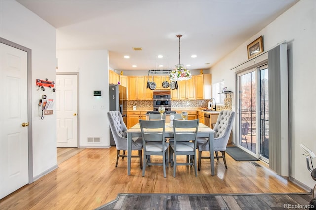 dining space with sink and light wood-type flooring