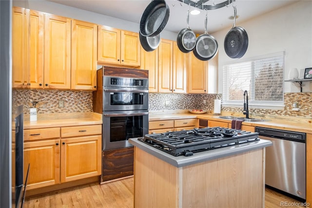 kitchen with stainless steel appliances, a center island, sink, and light hardwood / wood-style flooring