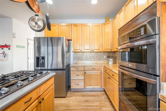 kitchen featuring appliances with stainless steel finishes, light hardwood / wood-style flooring, light brown cabinets, and decorative backsplash