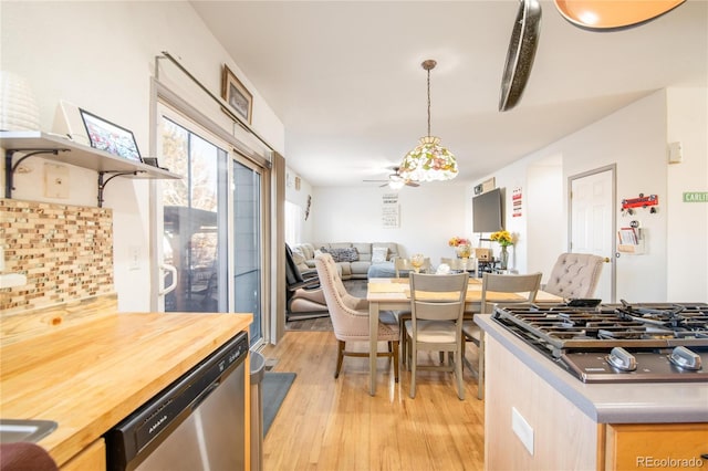 kitchen with pendant lighting, wood counters, decorative backsplash, stainless steel appliances, and light hardwood / wood-style flooring