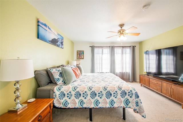 bedroom featuring ceiling fan, light colored carpet, and a textured ceiling