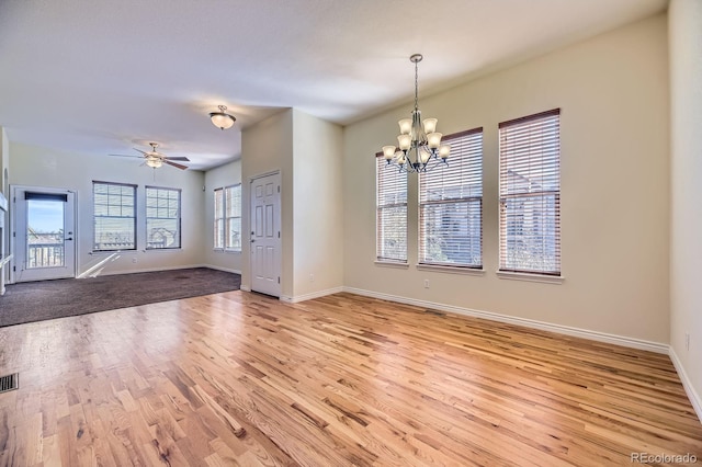 interior space with visible vents, baseboards, light wood-style floors, and ceiling fan with notable chandelier