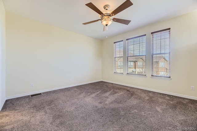 spare room with visible vents, baseboards, a ceiling fan, and dark carpet