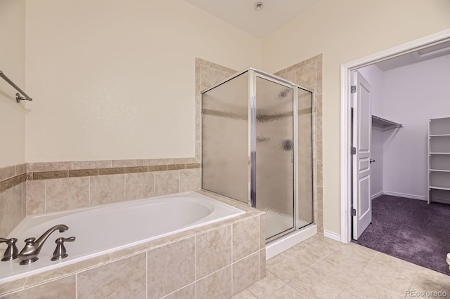 bathroom featuring a walk in closet, a shower stall, a bath, and tile patterned flooring