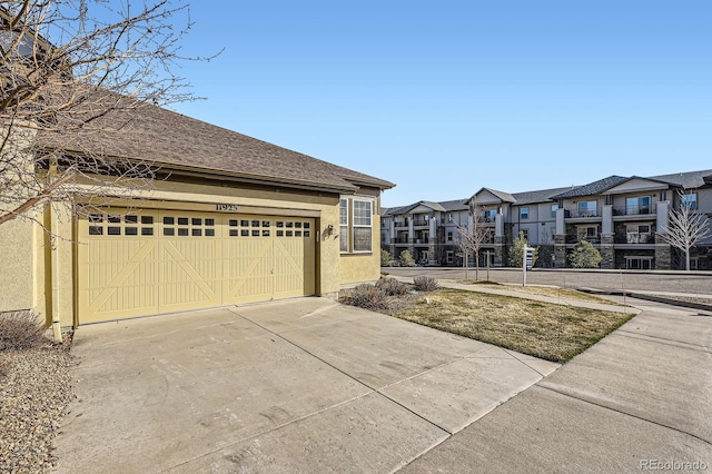 exterior space featuring a shingled roof, a residential view, driveway, and stucco siding