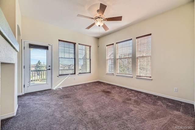 spare room with visible vents, baseboards, ceiling fan, and dark carpet