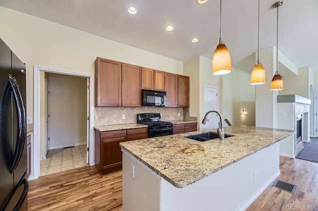 kitchen featuring brown cabinetry, visible vents, a sink, black appliances, and tasteful backsplash