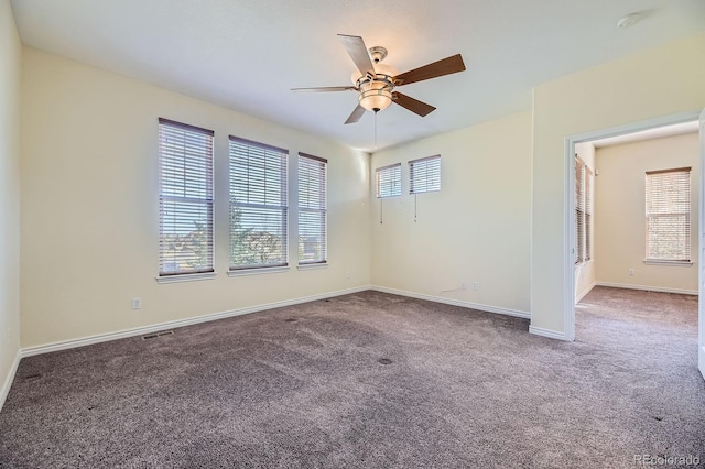 spare room featuring carpet flooring, visible vents, baseboards, and ceiling fan