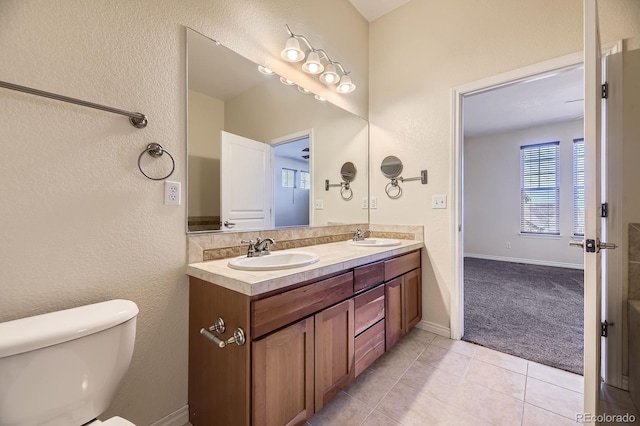 bathroom featuring a sink, toilet, double vanity, and tile patterned flooring