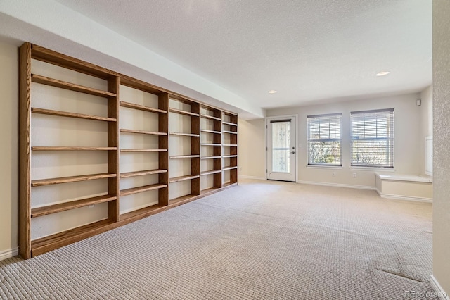 unfurnished living room with recessed lighting, light colored carpet, baseboards, and a textured ceiling