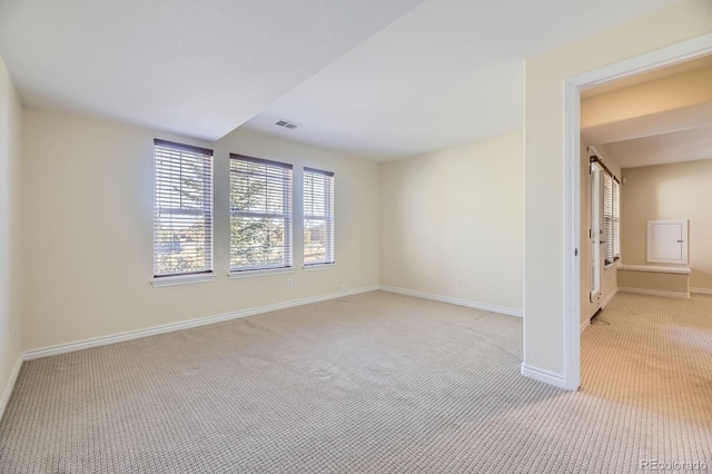 empty room with visible vents, baseboards, and light carpet