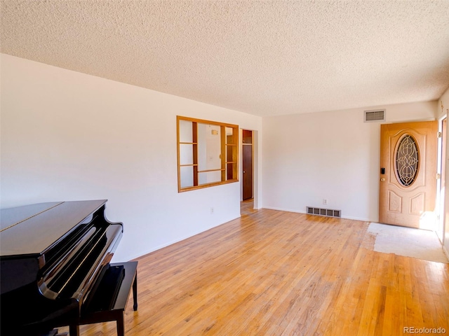 living room featuring a textured ceiling, hardwood / wood-style floors, and visible vents