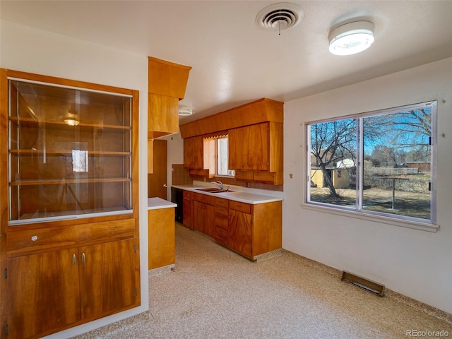 kitchen with light carpet, a sink, visible vents, light countertops, and brown cabinets