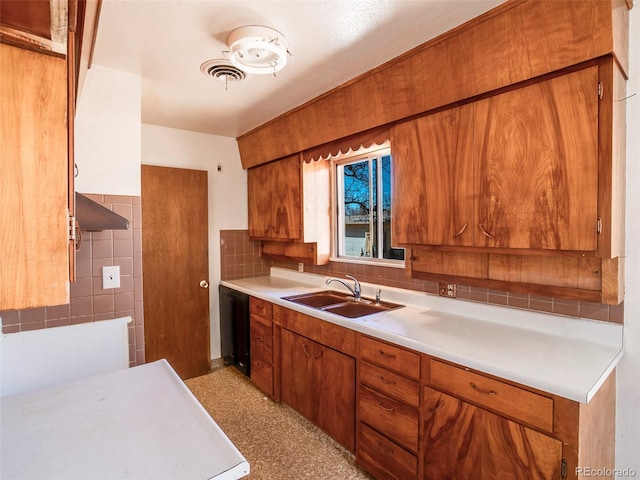 kitchen featuring light countertops, visible vents, backsplash, brown cabinetry, and a sink