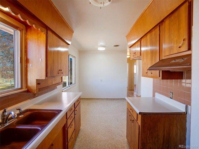 kitchen with decorative backsplash, a sink, visible vents, and brown cabinets