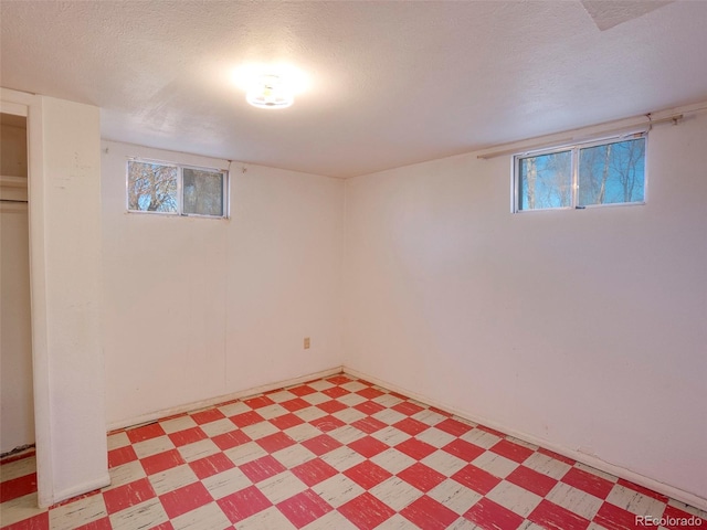 below grade area with a textured ceiling, light floors, and plenty of natural light