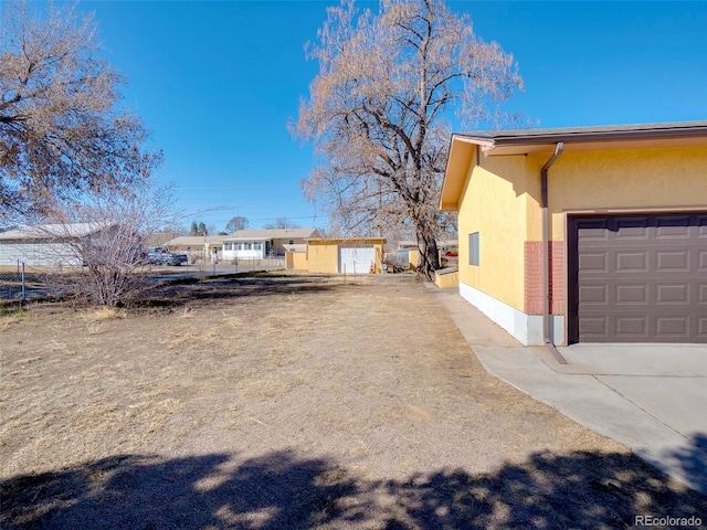 view of property exterior with a garage, driveway, brick siding, and stucco siding