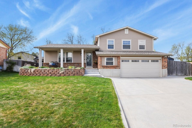 tri-level home with fence, a front yard, brick siding, an attached garage, and driveway