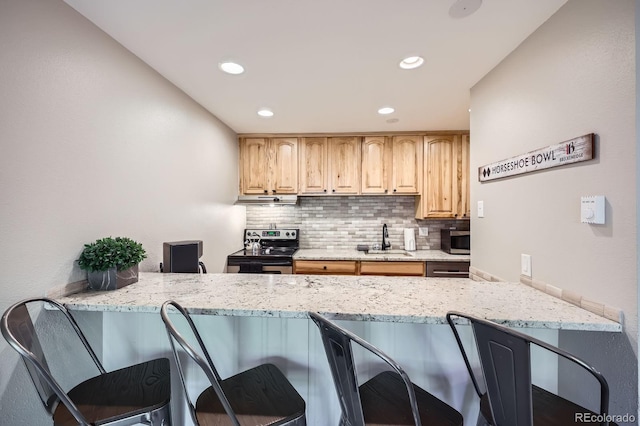 815 Columbine Rd Unit 22, Breckenridge, CO 80424 - kitchen featuring appliances with stainless steel finishes, under cabinet range hood, a peninsula, a kitchen bar, and recessed lighting