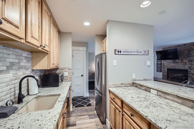 815 Columbine Rd Unit 22, Breckenridge, CO 80424 - kitchen with black microwave, freestanding refrigerator, light wood-type flooring, light stone counters, and a glass covered fireplace
