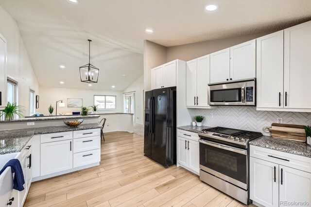 3455 Sun River Pl, Colorado Springs, CO 80920 - kitchen featuring appliances with stainless steel finishes, lofted ceiling, white cabinets, decorative backsplash, and stone countertops