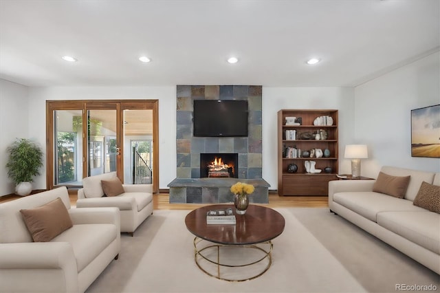 living room with a tile fireplace and light wood-type flooring