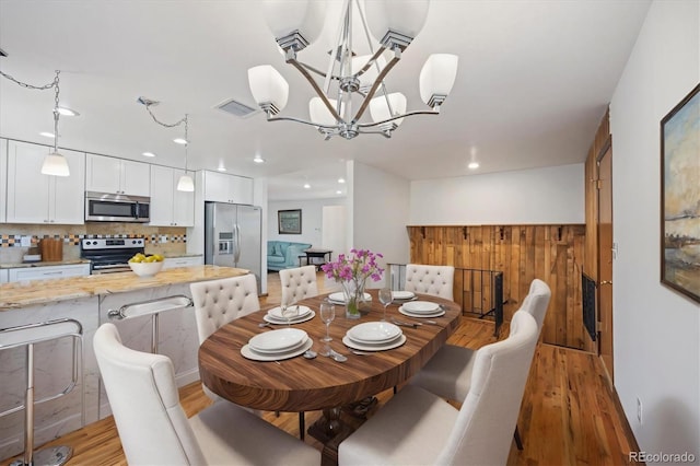 dining space with light hardwood / wood-style flooring and a notable chandelier