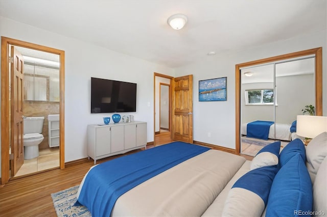 bedroom featuring a closet, ensuite bathroom, and light hardwood / wood-style flooring