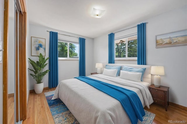 bedroom with multiple windows and hardwood / wood-style flooring