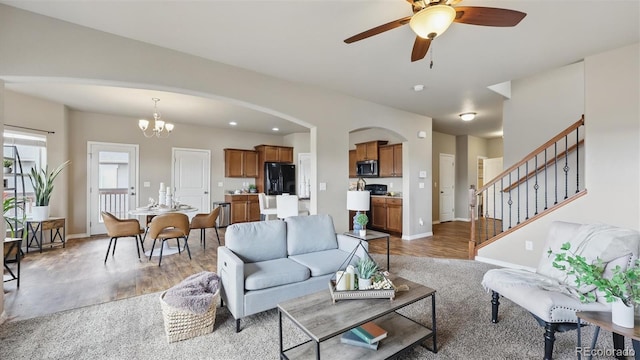 8308 Needle Drop Ct, Colorado Springs, CO 80908 - living area featuring ceiling fan, arched walkways, stairway, light wood-style flooring, and a chandelier