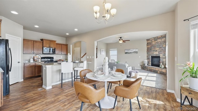 8308 Needle Drop Ct, Colorado Springs, CO 80908 - dining area with arched walkways, a ceiling fan, a stone fireplace, wood finished floors, and recessed lighting
