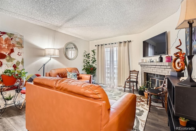 living area with a textured ceiling, a brick fireplace, and wood finished floors