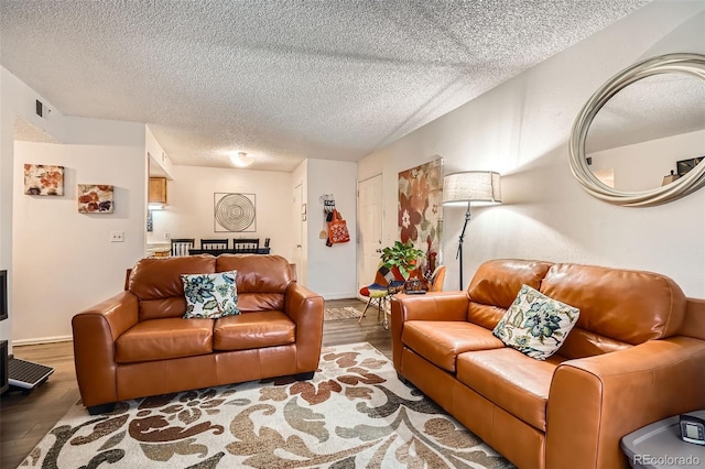 living room featuring a textured ceiling, visible vents, and wood finished floors