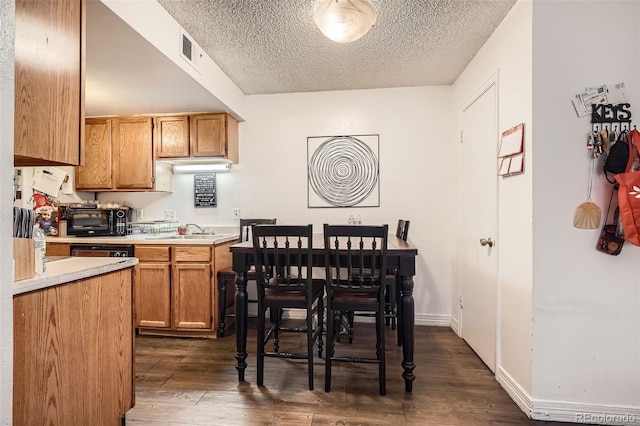 kitchen featuring a textured ceiling, a sink, visible vents, light countertops, and dark wood finished floors