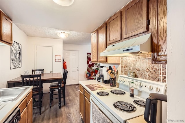 kitchen featuring brown cabinets, electric stove, light countertops, and under cabinet range hood