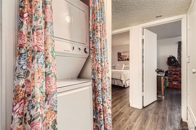 laundry room with laundry area, wood finished floors, a textured ceiling, and stacked washer and clothes dryer