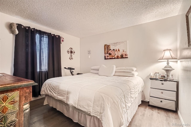 bedroom with a textured ceiling and wood finished floors