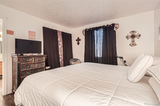 bedroom with a textured ceiling and wood finished floors