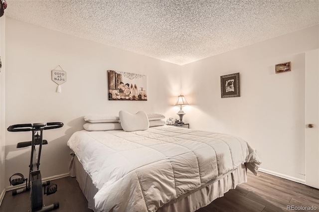 bedroom with a textured ceiling, dark wood finished floors, and baseboards