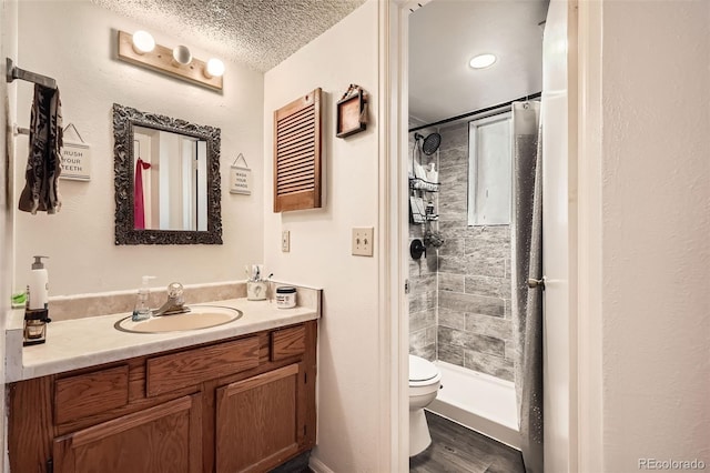 bathroom with a textured ceiling, a stall shower, vanity, and toilet