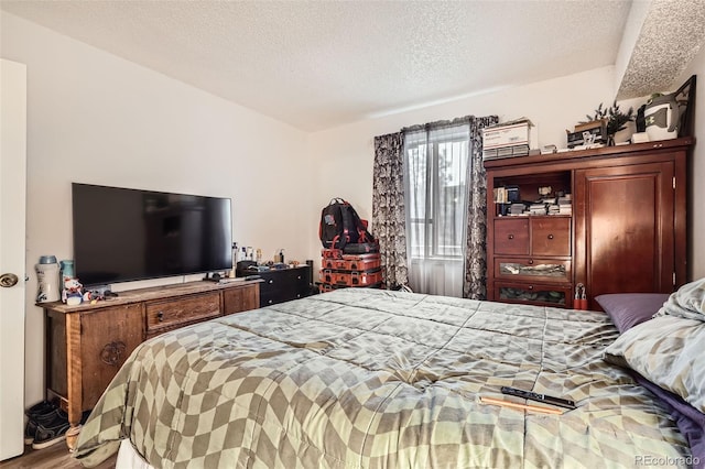 bedroom with a textured ceiling and wood finished floors