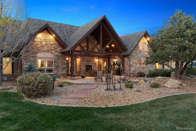 back house at dusk with a patio and a lawn