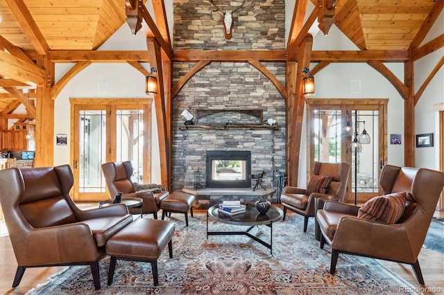 living room featuring high vaulted ceiling, a fireplace, beamed ceiling, wood ceiling, and light hardwood / wood-style flooring