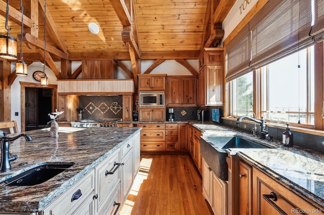 kitchen with white cabinetry, stainless steel microwave, dark stone counters, and sink