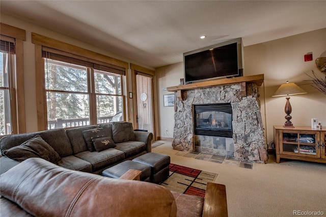 carpeted living room featuring a stone fireplace