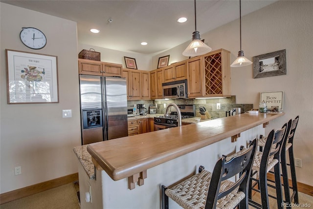 kitchen with a breakfast bar, kitchen peninsula, stainless steel appliances, and hanging light fixtures