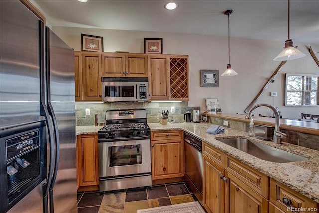 kitchen featuring pendant lighting, stainless steel appliances, light stone counters, and sink