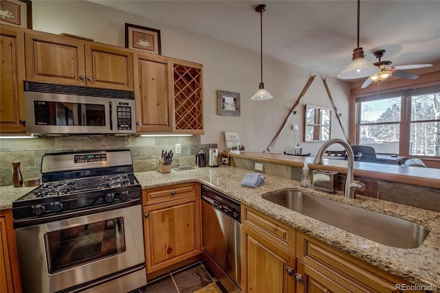 kitchen featuring appliances with stainless steel finishes, light stone counters, hanging light fixtures, and sink