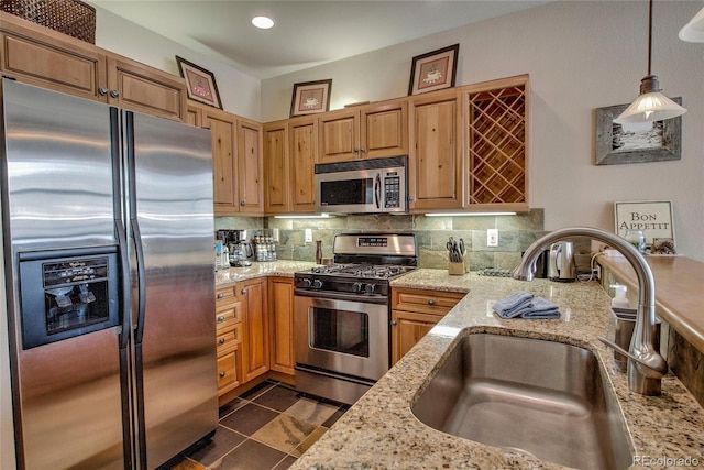 kitchen featuring sink, decorative backsplash, appliances with stainless steel finishes, decorative light fixtures, and light stone counters